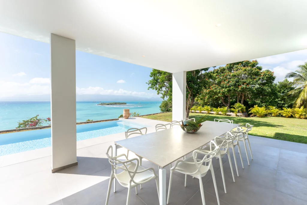 terrasse couverte vue mer avec table de repas et dix chaises blanches en Guadeloupe