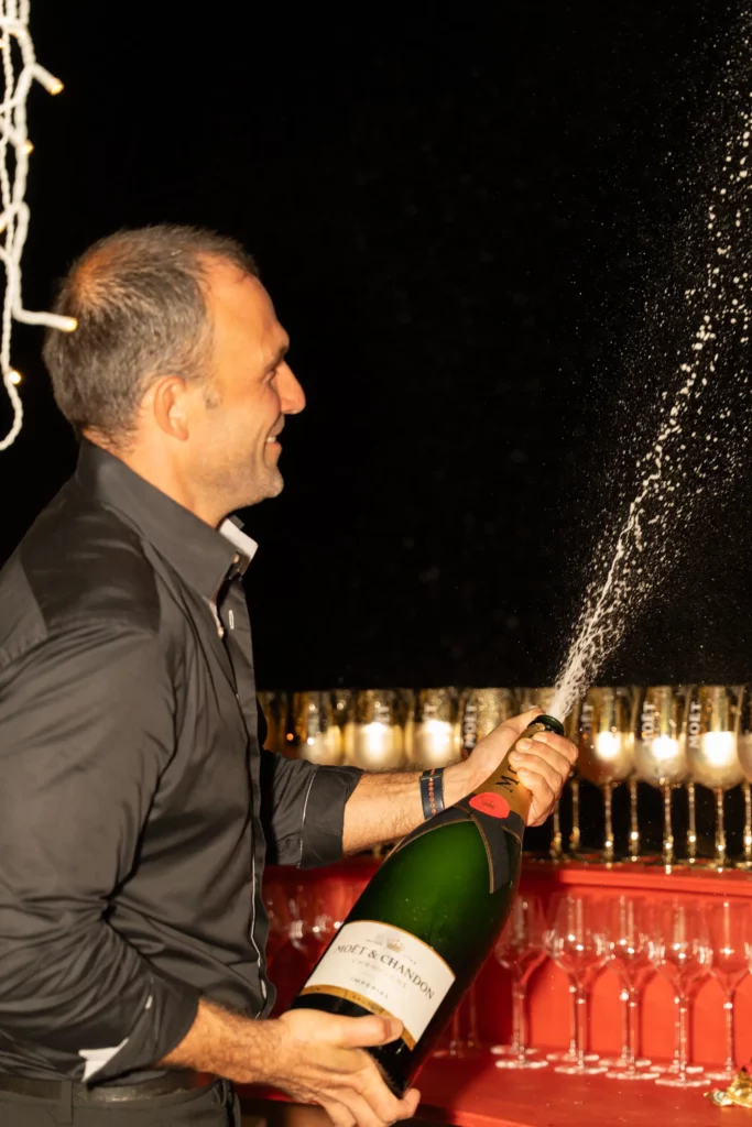 homme secouant une bouteille de champagne moet et chandon lors d'une soirée privée en villa en guadeloupe